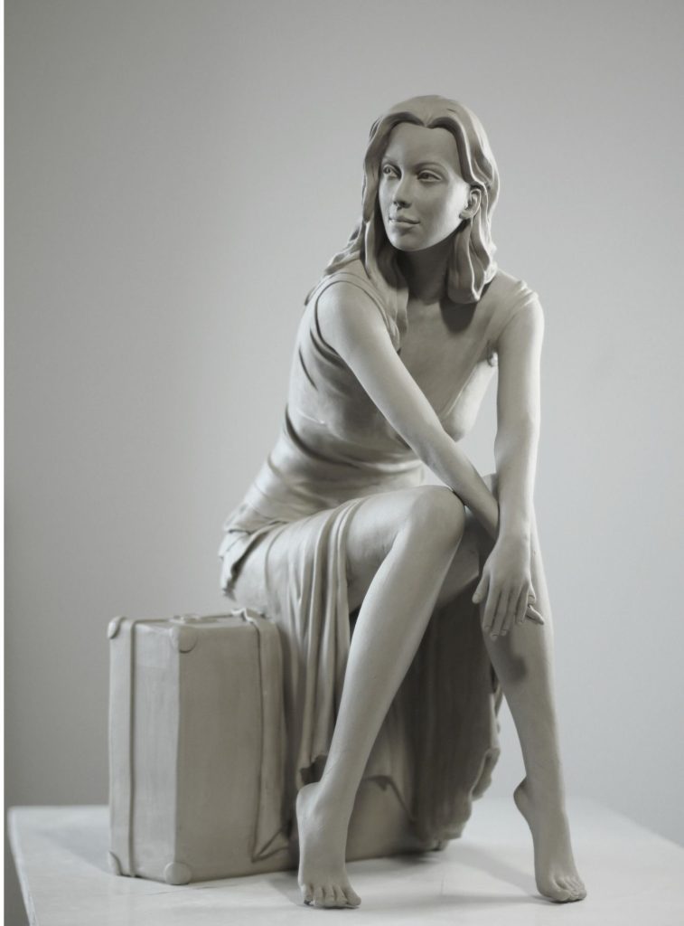 Sculpture en terre d’une femme assise sur une valise, vue avant.