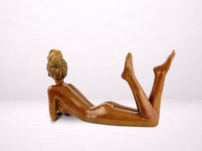 Sculpture en bronze d’une femme allongée sur le ventre, jambes relevées, vue de dos.