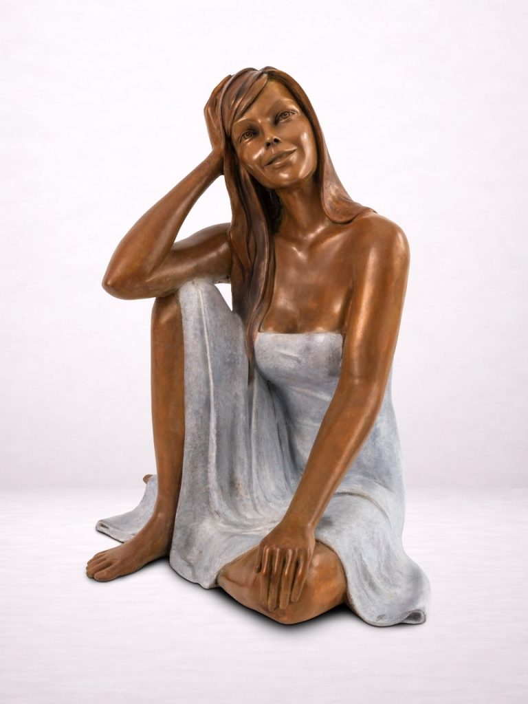 Sculpture en bronze d’une femme assise, vue de face.