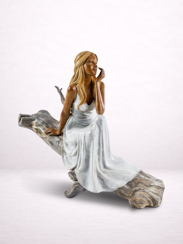 Sculpture en bronze d’une femme assise sur un tronc, vue avant.