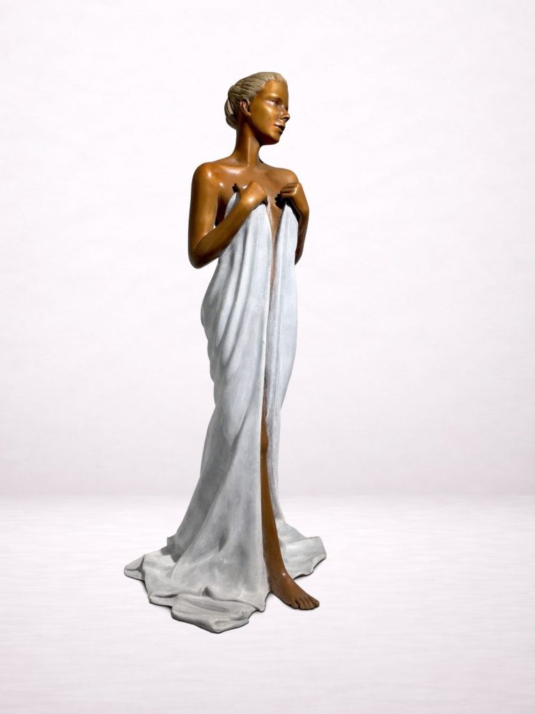 Sculpture en bronze d’une femme debout tenant un drapé, présentée dans un intérieur.