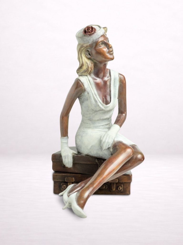 Sculpture en bronze d’une femme assise sur une valise, jambes croisées.