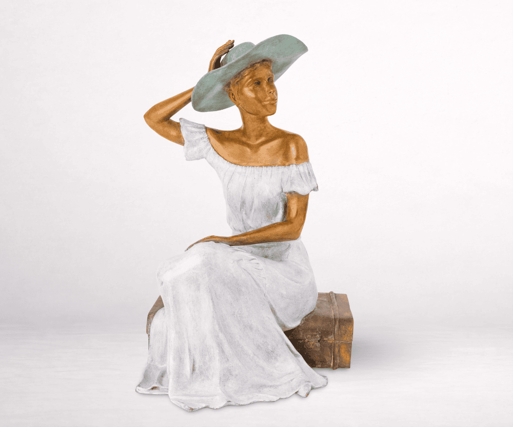 Sculpture en bronze d'une femme sur une valise et tenant son chapeau