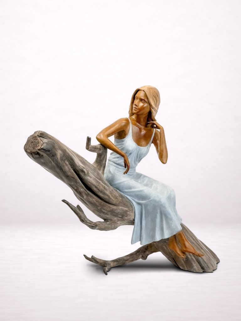 Sculpture en bronze d’une femme assise sur un tronc, vue trois-quarts avant.