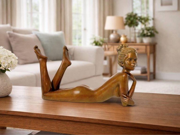 Sculpture en bronze d’une femme allongée sur le ventre, jambes relevées sur un meuble