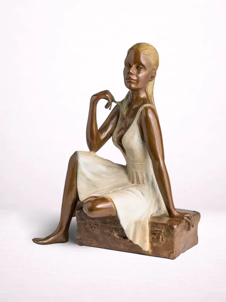 Sculpture en bronze d’une femme assise sur une valise, vue de face.
