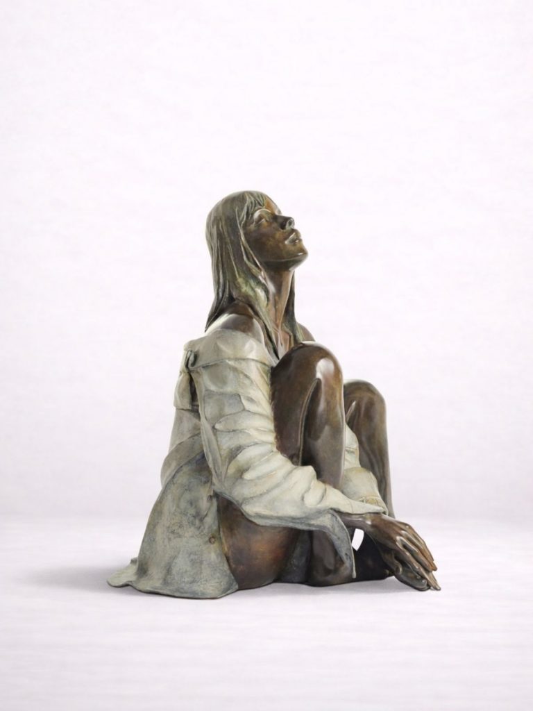 Sculpture en bronze d’une femme en chemise assise par terre, vue de profil