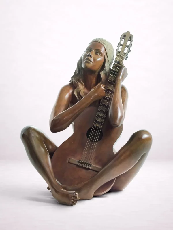 Sculpture en bronze d’une femme nue assise par terre et tenant une guitare contre elle.