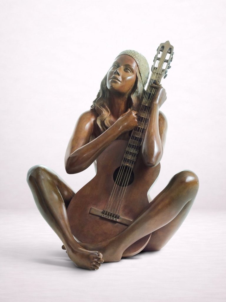 Sculpture en bronze d’une femme nue assise par terre et tenant une guitare contre elle.