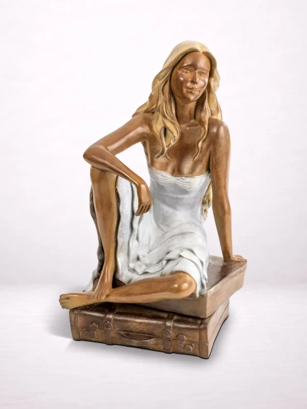 Sculpture en bronze d’une femme assise sur une valise, vue de face.