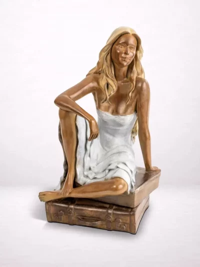 Sculpture en bronze d’une femme assise sur une valise, vue de face.