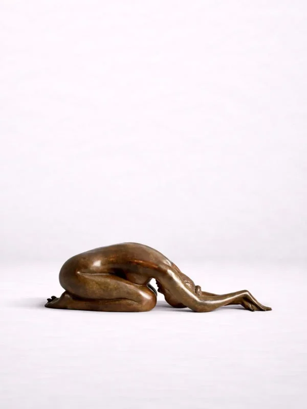 Sculpture en bronze d’une femme pliée et allongée sur ses genoux, tête baissée contre le sol.