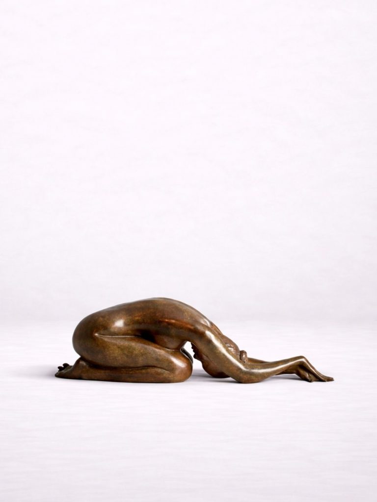 Sculpture en bronze d’une femme pliée et allongée sur ses genoux, tête baissée contre le sol.