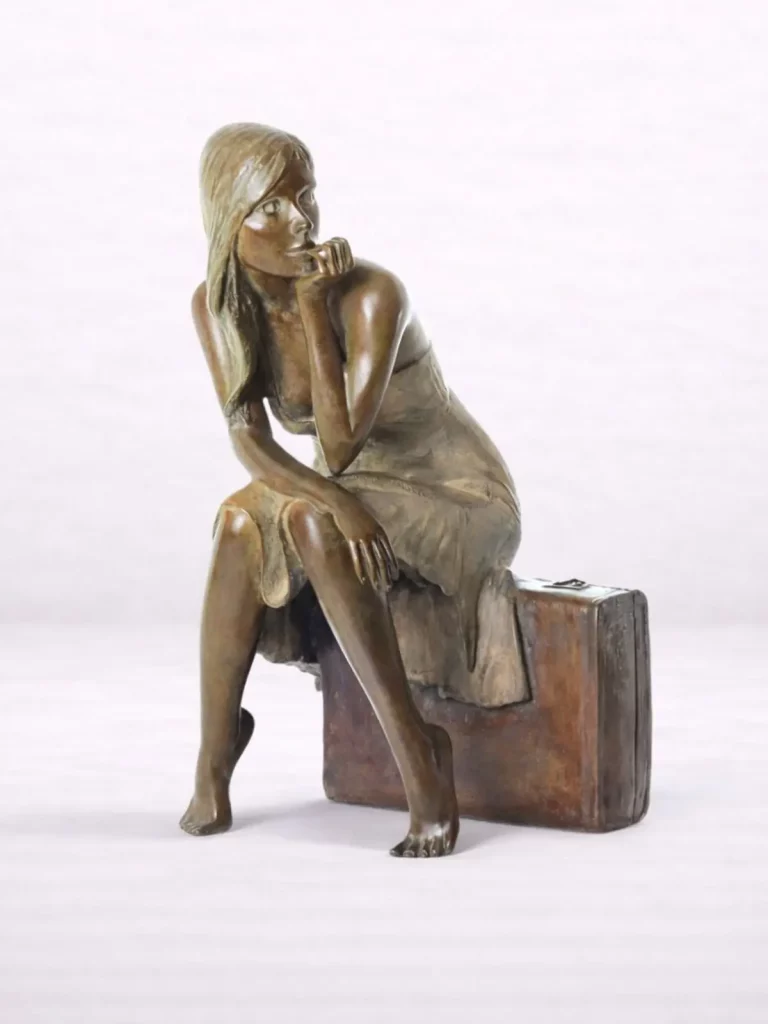 Sculpture en bronze d’une femme assise sur une valise, accoudée sur un genou, vue de face.