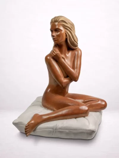 Sculpture en bronze d’une femme assise sur un coussin, vue de face en trois-quarts.