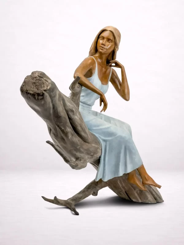 Sculpture en bronze d’une femme assise sur un tronc, vue avant.