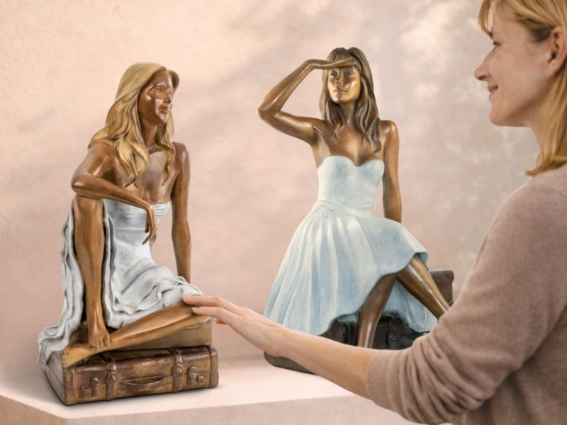 Sculpture en bronze femme assise sur valises observée de près par une femme dans une galerie