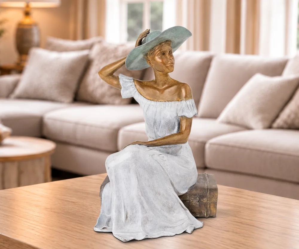 Sculpture en bronze contemporain Margaux, assise avec un chapeau, dans un salon élégant et lumineux.